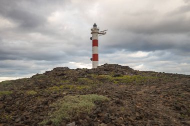 Volkanik kayalar, deniz feneri ve fırtına bulutlarıyla çöl manzarası. Aabdes, Tenerife, Kanarya Adaları. İspanya