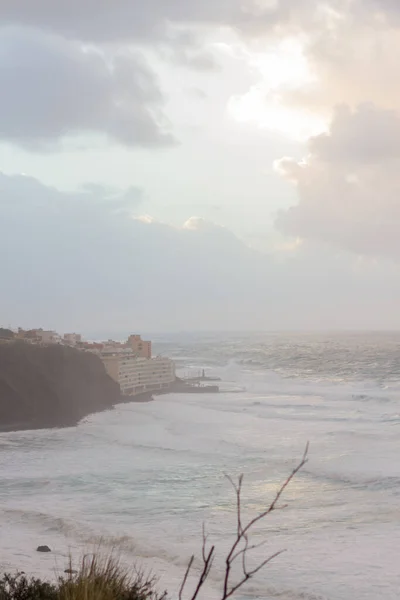 夕阳西下 陡峭的大海从悬崖上掠过 浪花汹涌 许多白色的泡沫冲刷着海岸 暴风雨般的云彩和风景如画的渔村 Bajamar Tenerife 加那利群岛 西班牙 — 图库照片