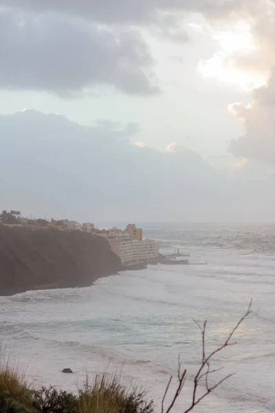 夕阳西下 陡峭的大海从悬崖上掠过 浪花汹涌 许多白色的泡沫冲刷着海岸 暴风雨般的云彩和风景如画的渔村 Bajamar Tenerife 加那利群岛 西班牙 — 图库照片