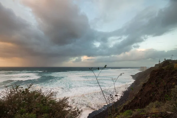 夕阳西下 陡峭的大海从悬崖上掠过 浪花汹涌 许多白色的泡沫冲刷着海岸 暴风雨般的云彩和风景如画的渔村 Bajamar Tenerife 加那利群岛 西班牙 — 图库照片