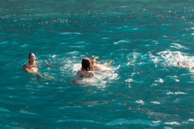 Bir grup insan, turistler, arka planda bir uçurumla Atlantik Okyanusu 'nun turkuaz sularında yüzüyorlar. Los Gigantes, Tenerife, Kanarya Adaları. İspanya