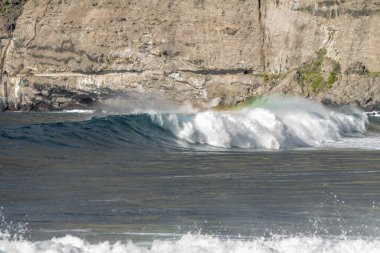 Bol köpüklü dalgalar, Atlantik Okyanusu 'nun volkanik siyah kumlu sahilinde, arka planda kayaları ve kayaları gören dalgalar. Los Gigantes, Tenerife, Kanarya Adaları 'ndan Cliff. İspanya