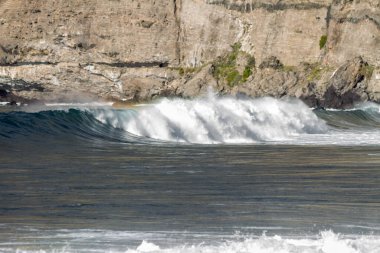 Bol köpüklü dalgalar, Atlantik Okyanusu 'nun volkanik siyah kumlu sahilinde, arka planda kayaları ve kayaları gören dalgalar. Los Gigantes, Tenerife, Kanarya Adaları 'ndan Cliff. İspanya