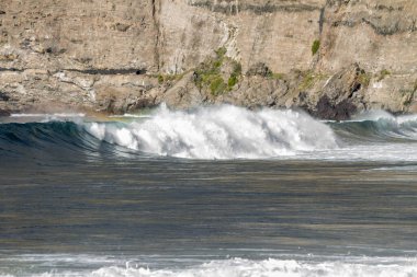 Bol köpüklü dalgalar, Atlantik Okyanusu 'nun volkanik siyah kumlu sahilinde, arka planda kayaları ve kayaları gören dalgalar. Los Gigantes, Tenerife, Kanarya Adaları 'ndan Cliff. İspanya