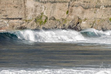 Bol köpüklü dalgalar, Atlantik Okyanusu 'nun volkanik siyah kumlu sahilinde, arka planda kayaları ve kayaları gören dalgalar. Los Gigantes, Tenerife, Kanarya Adaları 'ndan Cliff. İspanya