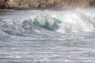 Bol köpüklü dalgalar, Atlantik Okyanusu 'nun volkanik siyah kumlu sahilinde, arka planda kayaları ve kayaları gören dalgalar. Los Gigantes, Tenerife, Kanarya Adaları 'ndan Cliff. İspanya