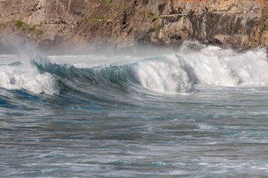 Bol köpüklü dalgalar, Atlantik Okyanusu 'nun volkanik siyah kumlu sahilinde, arka planda kayaları ve kayaları gören dalgalar. Los Gigantes, Tenerife, Kanarya Adaları 'ndan Cliff. İspanya