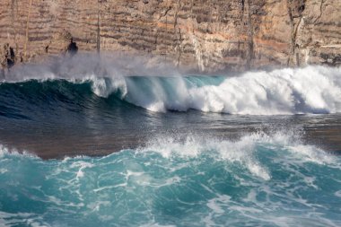 Bol köpüklü dalgalar, Atlantik Okyanusu 'nun volkanik siyah kumlu sahilinde, arka planda kayaları ve kayaları gören dalgalar. Los Gigantes, Tenerife, Kanarya Adaları 'ndan Cliff. İspanya