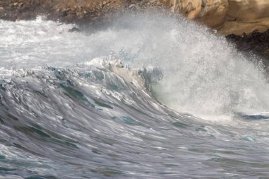 Bol köpüklü dalgalar, Atlantik Okyanusu 'nun volkanik siyah kumlu sahilinde, arka planda kayaları ve kayaları gören dalgalar. Los Gigantes, Tenerife, Kanarya Adaları 'ndan Cliff. İspanya