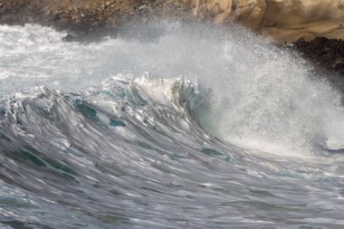 Bol köpüklü dalgalar, Atlantik Okyanusu 'nun volkanik siyah kumlu sahilinde, arka planda kayaları ve kayaları gören dalgalar. Los Gigantes, Tenerife, Kanarya Adaları 'ndan Cliff. İspanya