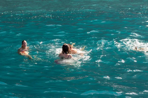 Bir grup insan, turistler, arka planda bir uçurumla Atlantik Okyanusu 'nun turkuaz sularında yüzüyorlar. Los Gigantes, Tenerife, Kanarya Adaları. İspanya