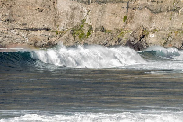 Bol köpüklü dalgalar, Atlantik Okyanusu 'nun volkanik siyah kumlu sahilinde, arka planda kayaları ve kayaları gören dalgalar. Los Gigantes, Tenerife, Kanarya Adaları 'ndan Cliff. İspanya