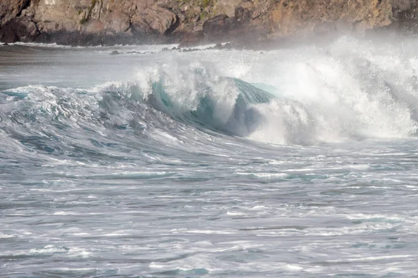 Bol köpüklü dalgalar, Atlantik Okyanusu 'nun volkanik siyah kumlu sahilinde, arka planda kayaları ve kayaları gören dalgalar. Los Gigantes, Tenerife, Kanarya Adaları 'ndan Cliff. İspanya
