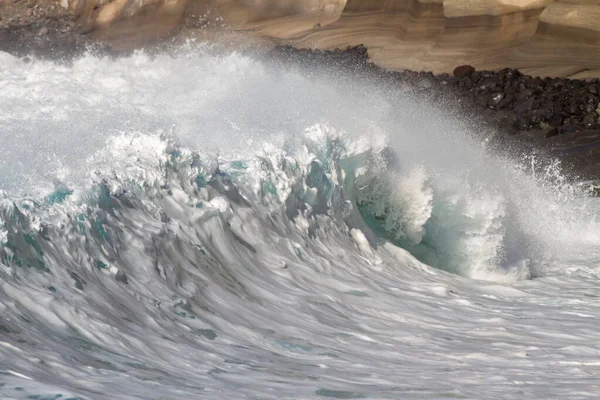 Bol köpüklü dalgalar, Atlantik Okyanusu 'nun volkanik siyah kumlu sahilinde, arka planda kayaları ve kayaları gören dalgalar. Los Gigantes, Tenerife, Kanarya Adaları 'ndan Cliff. İspanya