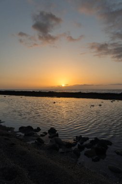 Sahilde gün batımı, altın güneş ışınları ve mavi gökyüzünde küçük bulutlar. Playa de Las Americas, Tenerife, Kanarya Adaları. İspanya