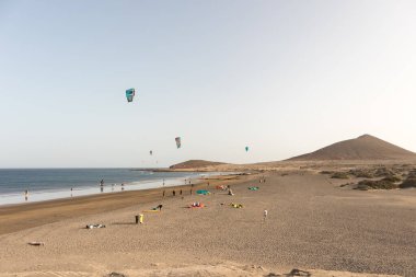 Deniz manzarası, sarı kumsal manzarası, çalılar uçurtma sörfü yapan insanlar ve arka planda Montana Roja. Paya Grande, El Medano, Tenerife, Kanarya Adaları. İspanya