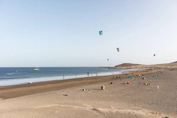 Deniz manzarası, sarı kumsal manzarası, çalılar uçurtma sörfü yapan insanlar ve arka planda Montana Roja. Paya Grande, El Medano, Tenerife, Kanarya Adaları. İspanya