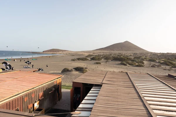 Deniz manzarası, sarı kumsal manzarası, çalılar uçurtma sörfü yapan insanlar ve arka planda Montana Roja. Paya Grande, El Medano, Tenerife, Kanarya Adaları. İspanya