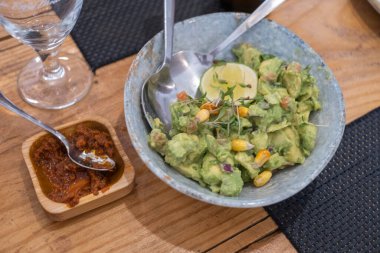 Haute yemek tabağı, avokado ceviche ve farklı sebzeler, gri bir el yapımı seramik kasede servis ediliyor, beyaz noktalı, antika bir masada. Tenerife, Kanarya Adaları, İspanya