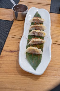 Üst manzara, yemek kabı, beyaz porselen bir tepside servis edilen haşlanmış etle dolu keseler ve yeşil bir yaprak ve eski bir masanın üzerinde uzun saplı küçük metal bir sos teknesi. Tenerife, Kanarya Adaları, İspanya