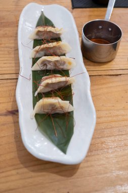 Üst manzara, yemek kabı, beyaz porselen bir tepside servis edilen haşlanmış etle dolu keseler ve yeşil bir yaprak ve eski bir masanın üzerinde uzun saplı küçük metal bir sos teknesi. Tenerife, Kanarya Adaları, İspanya