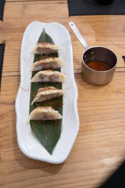 Üst manzara, yemek kabı, beyaz porselen bir tepside servis edilen haşlanmış etle dolu keseler ve yeşil bir yaprak ve eski bir masanın üzerinde uzun saplı küçük metal bir sos teknesi. Tenerife, Kanarya Adaları, İspanya