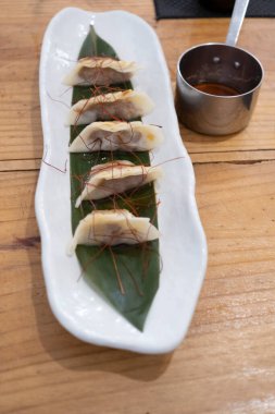 Üst manzara, yemek kabı, beyaz porselen bir tepside servis edilen haşlanmış etle dolu keseler ve yeşil bir yaprak ve eski bir masanın üzerinde uzun saplı küçük metal bir sos teknesi. Tenerife, Kanarya Adaları, İspanya