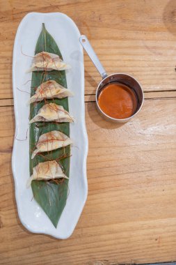 Üst manzara, yemek kabı, beyaz porselen bir tepside servis edilen haşlanmış etle dolu keseler ve yeşil bir yaprak ve eski bir masanın üzerinde uzun saplı küçük metal bir sos teknesi. Tenerife, Kanarya Adaları, İspanya