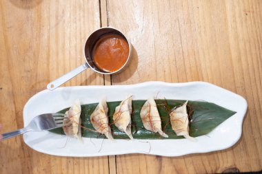 Üst manzara, yemek kabı, beyaz porselen bir tepside servis edilen haşlanmış etle dolu keseler ve yeşil bir yaprak ve eski bir masanın üzerinde uzun saplı küçük metal bir sos teknesi. Tenerife, Kanarya Adaları, İspanya