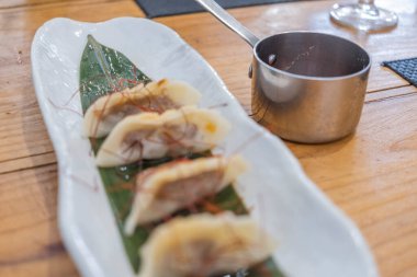 Haute mutfak tabağı, beyaz bir porselen tepside ve yeşil bir yaprak üzerinde servis edilen ağır ateşte pişirilmiş etle dolu keseler ve eski bir masanın üzerinde uzun saplı metal bir sos teknesi. Tenerife, Kanarya Adaları, İspanya