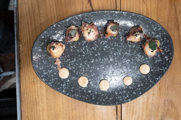 Eski bir masada siyah bir volkanik taş tepside sunulan küçük dilimler halinde kızarmış ahtapot yemek tabağının ayrıntıları. Tenerife, Kanarya Adaları, İspanya