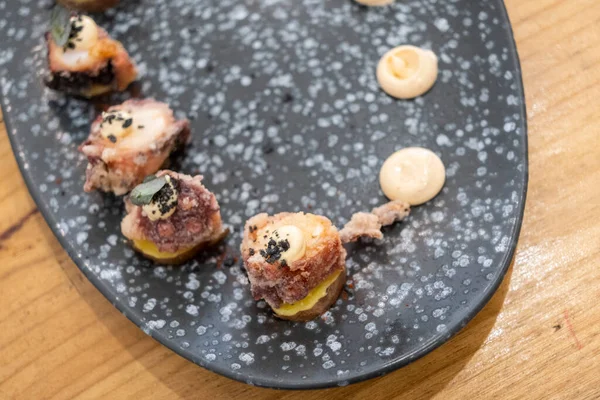 Eski bir masada siyah bir volkanik taş tepside sunulan küçük dilimler halinde kızarmış ahtapot yemek tabağının ayrıntıları. Tenerife, Kanarya Adaları, İspanya