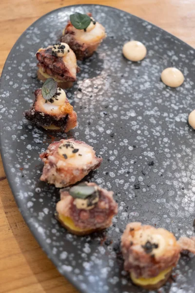 Eski bir masada siyah bir volkanik taş tepside sunulan küçük dilimler halinde kızarmış ahtapot yemek tabağının ayrıntıları. Tenerife, Kanarya Adaları, İspanya