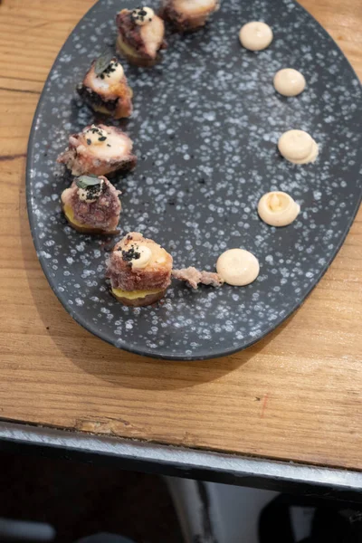 Eski bir masada siyah bir volkanik taş tepside sunulan küçük dilimler halinde kızarmış ahtapot yemek tabağının ayrıntıları. Tenerife, Kanarya Adaları, İspanya