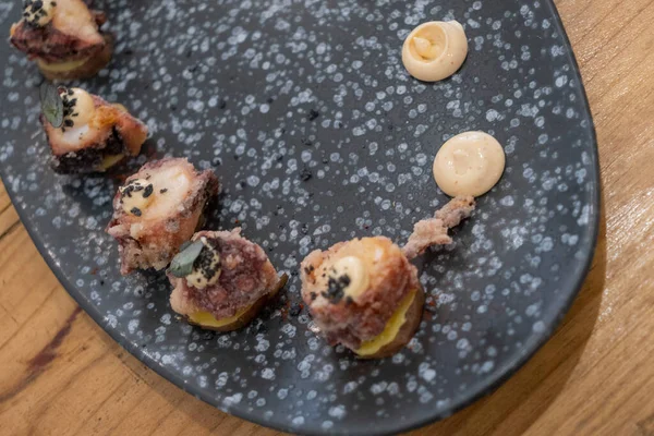 Eski bir masada siyah bir volkanik taş tepside sunulan küçük dilimler halinde kızarmış ahtapot yemek tabağının ayrıntıları. Tenerife, Kanarya Adaları, İspanya