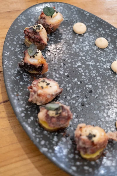 Eski bir masada siyah bir volkanik taş tepside sunulan küçük dilimler halinde kızarmış ahtapot yemek tabağının ayrıntıları. Tenerife, Kanarya Adaları, İspanya