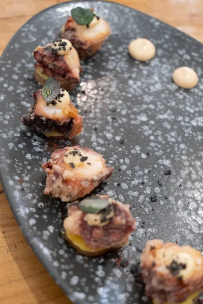 Eski bir masada siyah bir volkanik taş tepside sunulan küçük dilimler halinde kızarmış ahtapot yemek tabağının ayrıntıları. Tenerife, Kanarya Adaları, İspanya