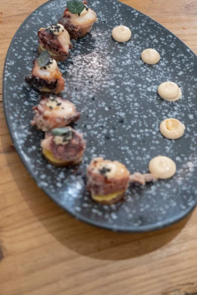 Eski bir masada siyah bir volkanik taş tepside sunulan küçük dilimler halinde kızarmış ahtapot yemek tabağının ayrıntıları. Tenerife, Kanarya Adaları, İspanya