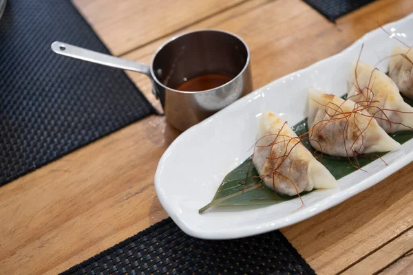 Üst manzara, yemek kabı, beyaz porselen bir tepside servis edilen haşlanmış etle dolu keseler ve yeşil bir yaprak ve eski bir masanın üzerinde uzun saplı küçük metal bir sos teknesi. Tenerife, Kanarya Adaları, İspanya