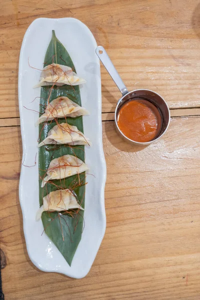 Üst manzara, yemek kabı, beyaz porselen bir tepside servis edilen haşlanmış etle dolu keseler ve yeşil bir yaprak ve eski bir masanın üzerinde uzun saplı küçük metal bir sos teknesi. Tenerife, Kanarya Adaları, İspanya