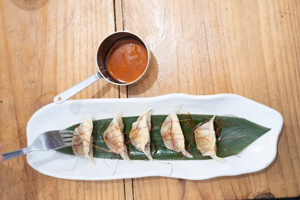 Üst manzara, yemek kabı, beyaz porselen bir tepside servis edilen haşlanmış etle dolu keseler ve yeşil bir yaprak ve eski bir masanın üzerinde uzun saplı küçük metal bir sos teknesi. Tenerife, Kanarya Adaları, İspanya