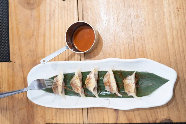 Haute mutfak tabağı, beyaz bir porselen tepside ve yeşil bir yaprak üzerinde servis edilen ağır ateşte pişirilmiş etle dolu keseler ve eski bir masanın üzerinde uzun saplı metal bir sos teknesi. Tenerife, Kanarya Adaları, İspanya