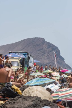 TENERİFE, SPAIN 11 - AGUSTAN 2013: Bir grup insan günü plajda şemsiyelerle, mayolarıyla, güneşlenerek, sahilde yüzerek ve kıyıdan badiba şampiyonasını izleyerek geçiriyorlar. Tenerife, Kanarya Adaları, Sp