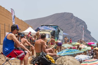 TENERİFE, SPAIN 11 - AGUSTAN 2013: Bir grup insan günü plajda şemsiyelerle, mayolarıyla, güneşlenerek, sahilde yüzerek ve kıyıdan badiba şampiyonasını izleyerek geçiriyorlar. Tenerife, Kanarya Adaları, Sp