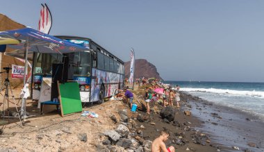 TENERİFE, SPAIN 11 - AGUSTAN 2013: Bir grup insan günü plajda şemsiyelerle, mayolarıyla, güneşlenerek, sahilde yüzerek ve kıyıdan badiba şampiyonasını izleyerek geçiriyorlar. Tenerife, Kanarya Adaları, Sp