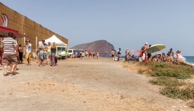 TENERİFE, SPAIN 11 - AGUSTAN 2013: Bir grup insan günü plajda şemsiyelerle, mayolarıyla, güneşlenerek, sahilde yüzerek ve kıyıdan badiba şampiyonasını izleyerek geçiriyorlar. Tenerife, Kanarya Adaları, Sp