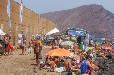 TENERİFE, SPAIN 11 - AGUSTAN 2013: Bir grup insan günü plajda şemsiyelerle, mayolarıyla, güneşlenerek, sahilde yüzerek ve kıyıdan badiba şampiyonasını izleyerek geçiriyorlar. Tenerife, Kanarya Adaları, Sp