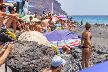TENERİFE, SPAIN 11 - AGUSTAN 2013: Bir grup insan günü plajda şemsiyelerle, mayolarıyla, güneşlenerek, sahilde yüzerek ve kıyıdan badiba şampiyonasını izleyerek geçiriyorlar. Tenerife, Kanarya Adaları, Sp