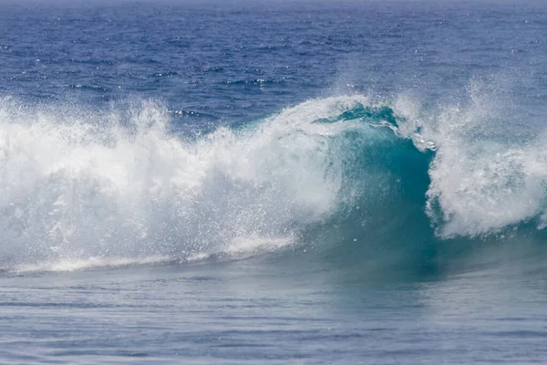 Kıyı şeridine doğru kopan bir dalganın yakın plan görüntüsü çok sayıda beyaz köpük oluşturur. Tenerife, Kanarya Adaları, İspanya