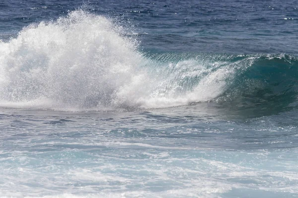 Kıyı şeridine doğru kopan bir dalganın yakın plan görüntüsü çok sayıda beyaz köpük oluşturur. Tenerife, Kanarya Adaları, İspanya